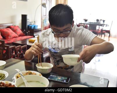 (160721)--Peking, 21. Juli 2016 (Xinhua)--Wang Taotao schaut auf sein Handy wie er Mahlzeit zu Hause in Shanghai, Ost-China, 30. Juni 2016 hat. Wang Taotao, geboren 1989, ist eine klassische Indoorsman, die einst ein professioneller Spieler für ein Online-Spiel. Seine Aufgabe ist jetzt Webcast seine Interpretation wie er Spiele spielt. Als Gastgeber des Spiels Webcast mit einem guten Ruf im Internet besitzt Wang zahlreicher Zuschauer und Fans. Wang Webcasts arbeitet fast jeden Tag mit mehr als fünf Stunden pro Tag und seine Frau, auch eine Gastgeberin Spiel Webcast mit ihm. Wang verdient seinen Lebensunterhalt durch Webcast, aus denen er durch bezahlt wird Stockfoto