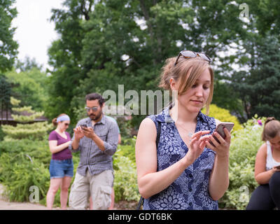 Columbus, Ohio, USA, 21. Juli 2016: Millennials sowohl ein junger Mann als auch junge Frauen spielen Pokemon Go im Park der Rosen. Pokemon Go ist ein standortbasiertes Augmented Reality-Mobilspiel, das von Niantic Labs unter Verwendung der beliebten Nintendo-Videospiele-Action-Figuren entwickelt wurde.Credit: 2016 Marianne A. Campolongo/Alamy Live News. Stockfoto