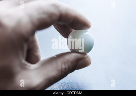 menschliche Finger halten einer Glaskugel hautnah Stockfoto