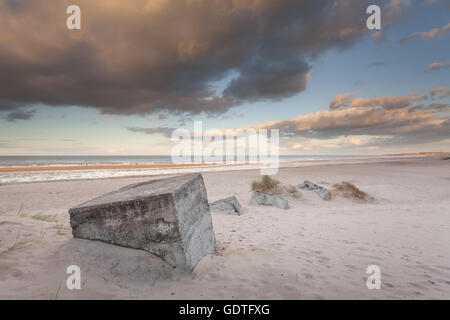 Würfel halb vergraben im Sand am Strand Cresswell, an der Northumberland Küste bei Sonnenuntergang Stockfoto