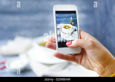 Frau, die ein Foto von Fischsuppe mit Smartphone. Nahaufnahme Stockfoto