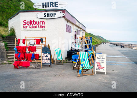 Surf-Schule, die aufbauend auf der Promenade am Saltburn vom Meer-Surf-Equipment und Siuts Liegestühlen und Windschutz zu mieten Stockfoto