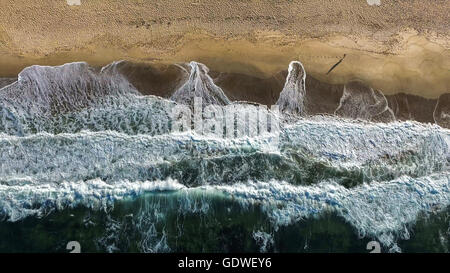 Luftaufnahme des Gehens Mann an einem Strand mit Wellen brechen. Stockfoto