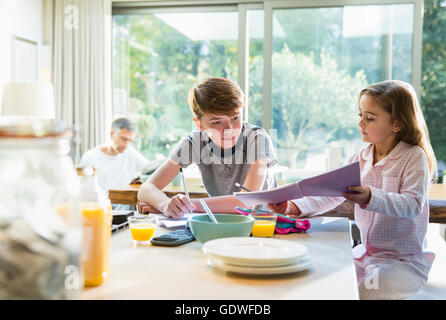 Bruder und Schwester zu frühstücken und Hausaufgaben Stockfoto