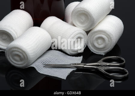 Medizinische Bandage mit einer Schere auf schwarzem Hintergrund Stockfoto