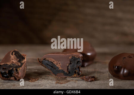 Pflaumen in Schokolade auf rustikalen hölzernen Hintergrund Stockfoto