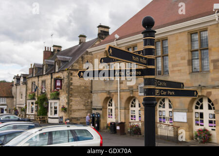 Metall Guss finger Post führen Fußgänger in Helmsley der malerischen Marktplatz, North Yorkshire, England - Rathaus gelegen hinter ist. Stockfoto