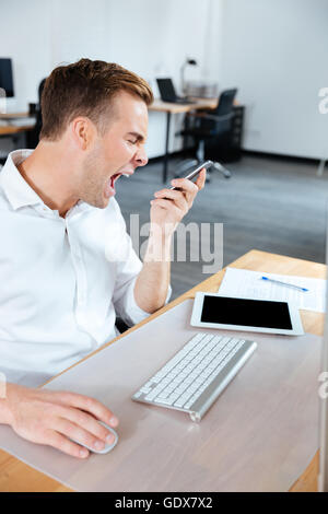 Wütend verrückt Jungunternehmer telefonieren mit Handy und rief im Büro Stockfoto