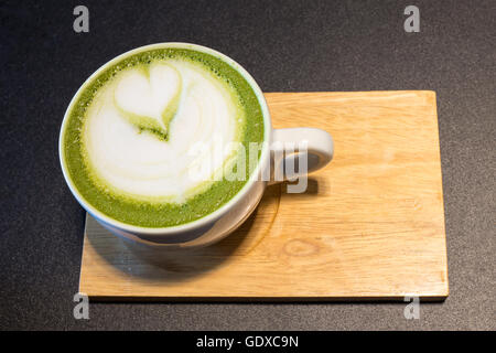 Tasse Latte Kunst auf Holz, grüner Tee Milch Kaffee Stockfoto