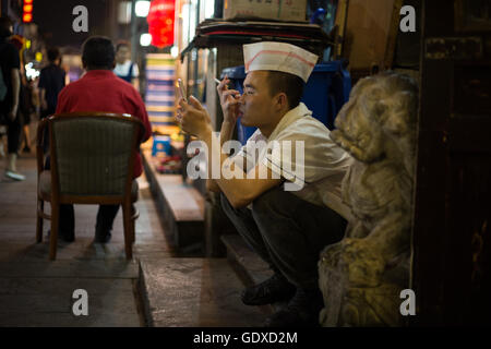 Chinesische Jugendliche spielen Sie mit ihren Smartphones und soziale Netzwerke in Peking, China Stockfoto