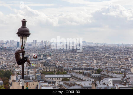 Akrobat jongliert mit einem Fußball auf einen Laternenpfahl in Montmartre, Paris, Frankreich, 2014 Stockfoto