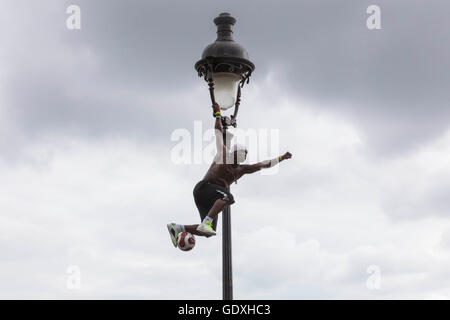 Akrobat jongliert mit einem Fußball auf einen Laternenpfahl in Montmartre, Paris, Frankreich, 2014 Stockfoto