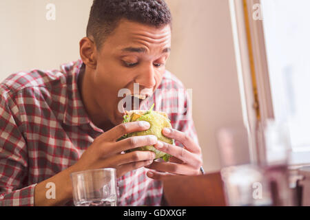 Mann isst Vegan Burger im restaurant Stockfoto