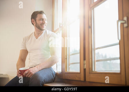 Architekt auf der Fensterbank sitzen und Tasse Kaffee, Bayern, Deutschland Stockfoto