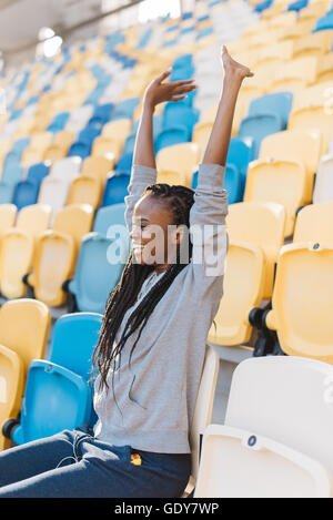 Ventilatoren: aufgeregt weiblicher Fan sitzt allein hinauf in die hohen Sitze, Seitenansicht Stockfoto