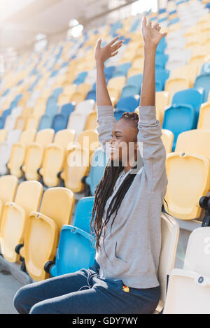 Glückliche junge afroamerikanische Frau unterstützen mit ihren Armen ausgelöst, Team oder feiern Ziel auf große Stadion Stockfoto
