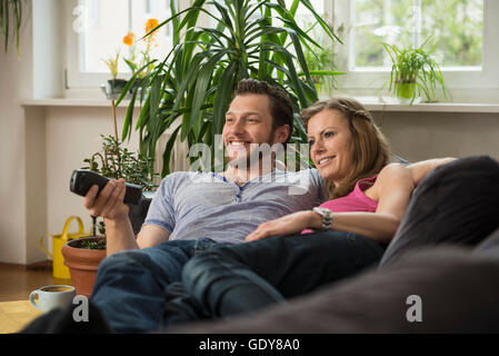 Paar vor dem Fernseher im Wohnzimmer, München, Bayern, Deutschland Stockfoto