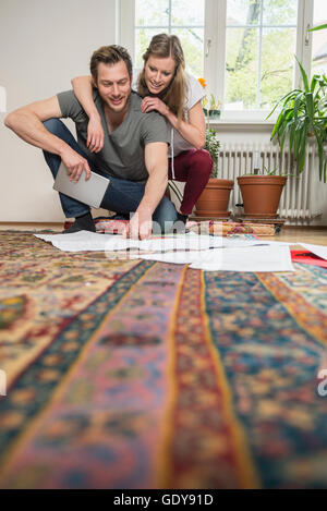 Paar auf der Suche auf Karte im Wohnzimmer, München, Bayern, Deutschland Stockfoto