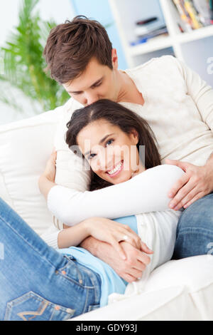 Porträt von schönen jungen Mann seine liebende Frau zu küssen, während sie entspannen zu Hause. Stockfoto