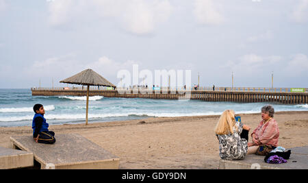 DURBAN, Südafrika - 17. August 2015: Leute sitzen in der Nähe der Pier am Nordstrand auf der Golden Mile Promenade. Stockfoto