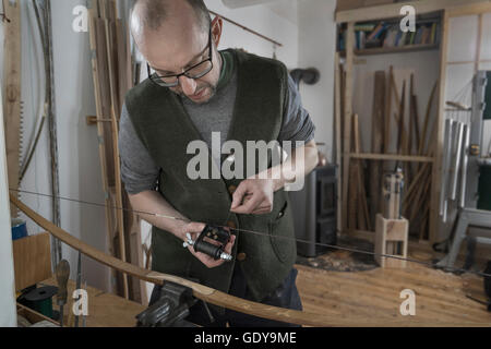 Männliche Bogenmacher Anpassung der Bogensehne in Werkstatt, Bayern, Deutschland Stockfoto