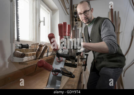 Männliche Bogenmacher Befestigung Holz in Form von Bogen in Werkstatt, Bayern, Deutschland Stockfoto