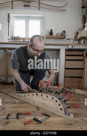 Männliche Bogenmacher Befestigung Holz in Form von Bogen in Werkstatt, Bayern, Deutschland Stockfoto