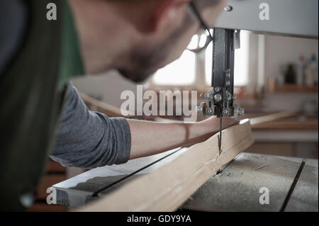 Männliche Bogenmacher Sägen von Holz mit einer Bandsäge, Bayern, Deutschland Stockfoto