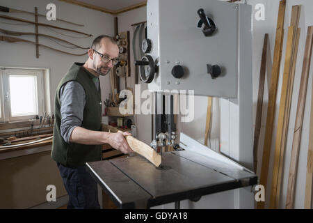 Männliche Bogenmacher Sägen von Holz mit einer Bandsäge, Bayern, Deutschland Stockfoto