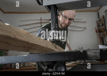 Männliche Bogenmacher Sägen von Holz mit einer Bandsäge, Bayern, Deutschland Stockfoto