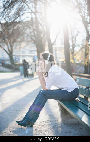 Reife Frau Musikhören und sitzen in der Park Bench, Bayern, Deutschland Stockfoto