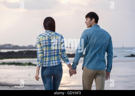 Rückseite des junges Paar hand in hand am Strand gehen Stockfoto