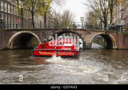 AMSTERDAM, Niederlande - 15. November 2015: Rote Sightseeing-Boot segeln durch die Amsterdamer Grachten. Die Stadt zählt 165 Kanal Stockfoto