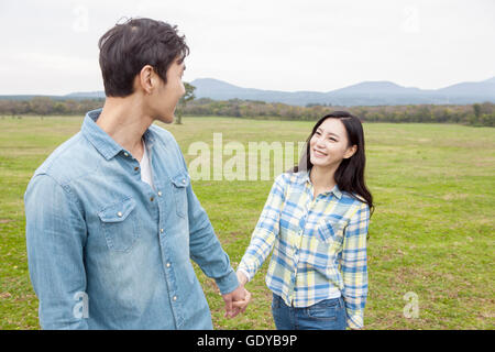 Porträt der jungen Frau haltende Hand lächelnd, mit einem Mann auf Grünland Stockfoto