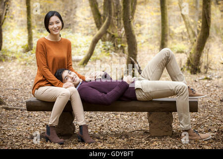 Junge, lächelnde paar mit einem Date auf einer Bank, starrte auf Vorderseite im Wald im Herbst Stockfoto