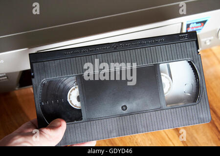 Mans Hand einfügen VHS leer Kassette in einen VHS-player Stockfoto