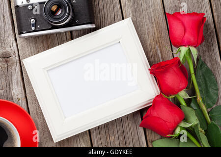 Valentinstag-Rosen, Fotorahmen, Retro-Kamera und Kaffeetasse über hölzerne Hintergrund Stockfoto
