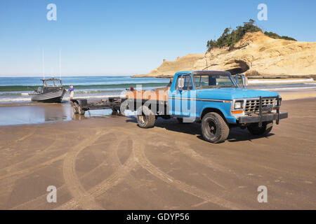 Eine Fischerei Dory ist vom Meer von seinem Besitzer am Strand von Cape Kiwanda in der Nähe von Pacific City abgerufen, Oregon.Cape Kiwanda ist eine Stockfoto