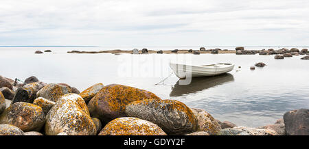 Weißes Boot hinter großen runden Felsen an einem bewölkten Tag Rudern Stockfoto