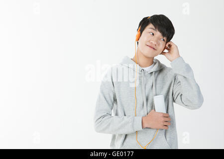 Porträt des Lächelns Schuljunge anhören von Musik auf MP3-player Stockfoto