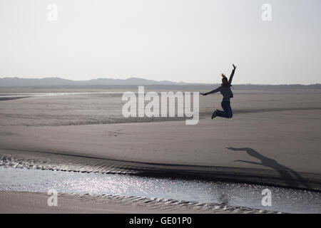 Mitte Erwachsene Frau springen in der Luft am Strand, Renesse, Schouwen-Duiveland, Zeeland, Niederlande Stockfoto