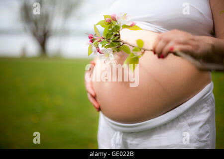 Schwangere Frau mit Kirsche Blumen stehen am Seeufer, Ammersee, Upper Bavaria, Bavaria, Germany Stockfoto