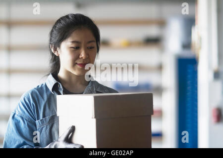 Junge Ingenieurin hält Karton in einer Industrieanlage, Freiburg Im Breisgau, Baden-Württemberg, Deutschland Stockfoto