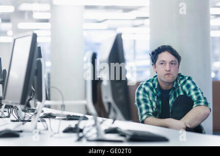 Mitte erwachsener Mann im Büro zu sitzen und zu denken, Freiburg Im Breisgau, Baden-Württemberg, Deutschland Stockfoto