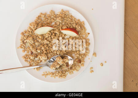Müsli Essen mit Scheiben von Apple und Löffel in Platte, Freiburg Im Breisgau, Baden-Württemberg, Deutschland Stockfoto