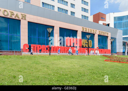 Gruppe von Kindern zu Fuß vorbei an solid 3D label "Herzlichen Glückwunsch, Liebe Stadt!" in der Nähe von the Business centre 'Grün' Stockfoto