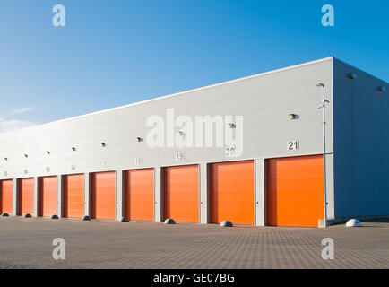außen eine gewerbliche Lagerhalle mit orange Rolltore Stockfoto