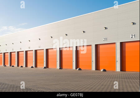 außen eine gewerbliche Lagerhalle mit orange Rolltore Stockfoto