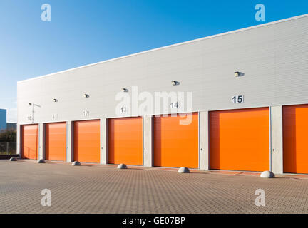 außen eine gewerbliche Lagerhalle mit orange Rolltore Stockfoto