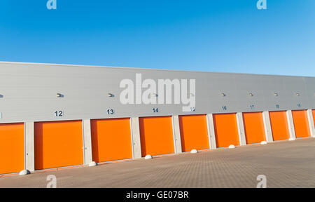 außen eine gewerbliche Lagerhalle mit orange Rolltore Stockfoto